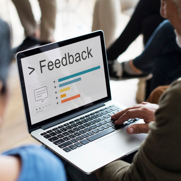 Hands typing on a laptop showing a feedback form in an office.