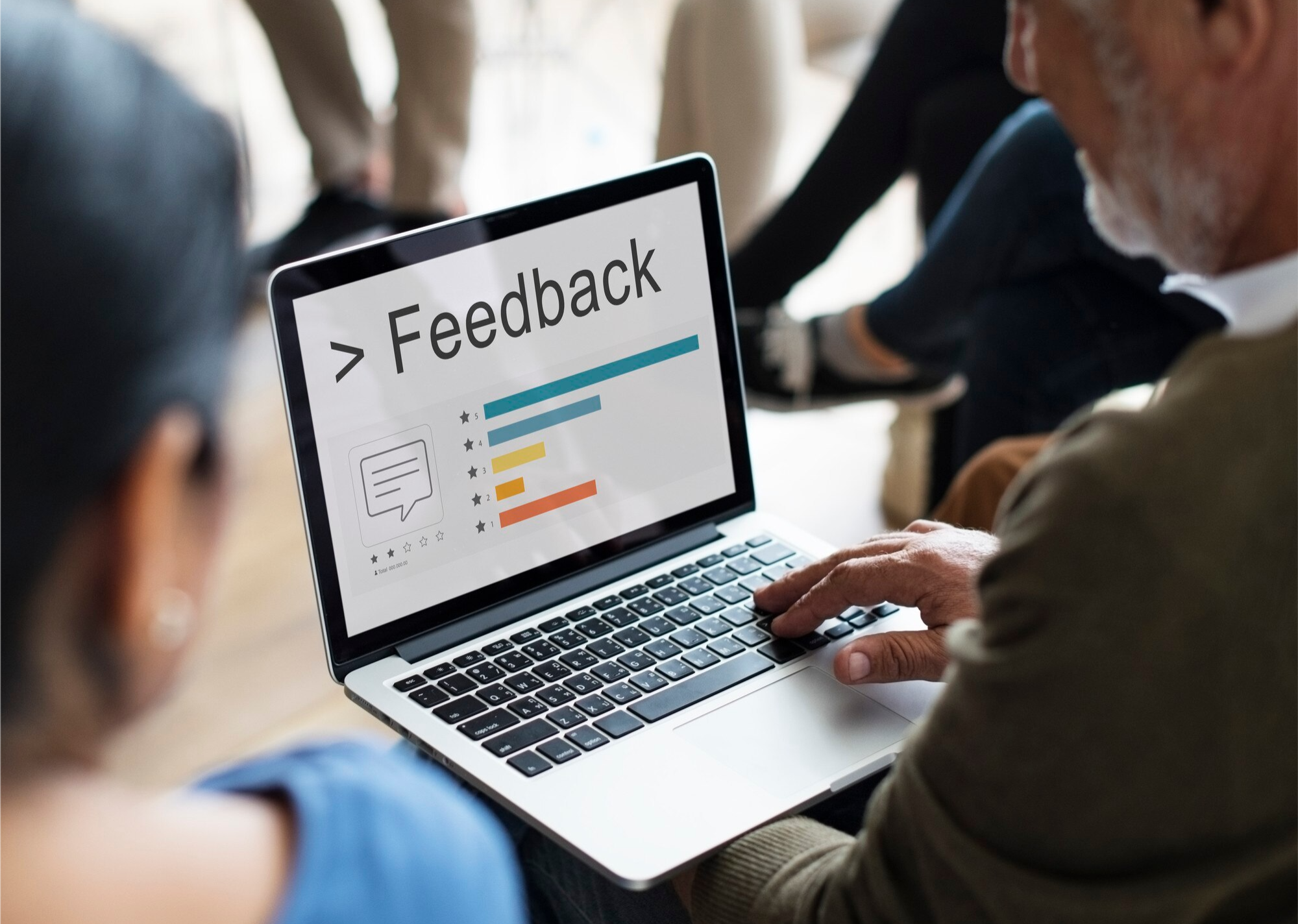 Hands typing on a laptop showing a feedback form in an office.