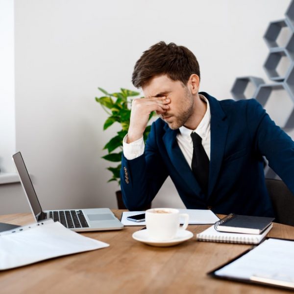 Employee holding his head with one hand while working