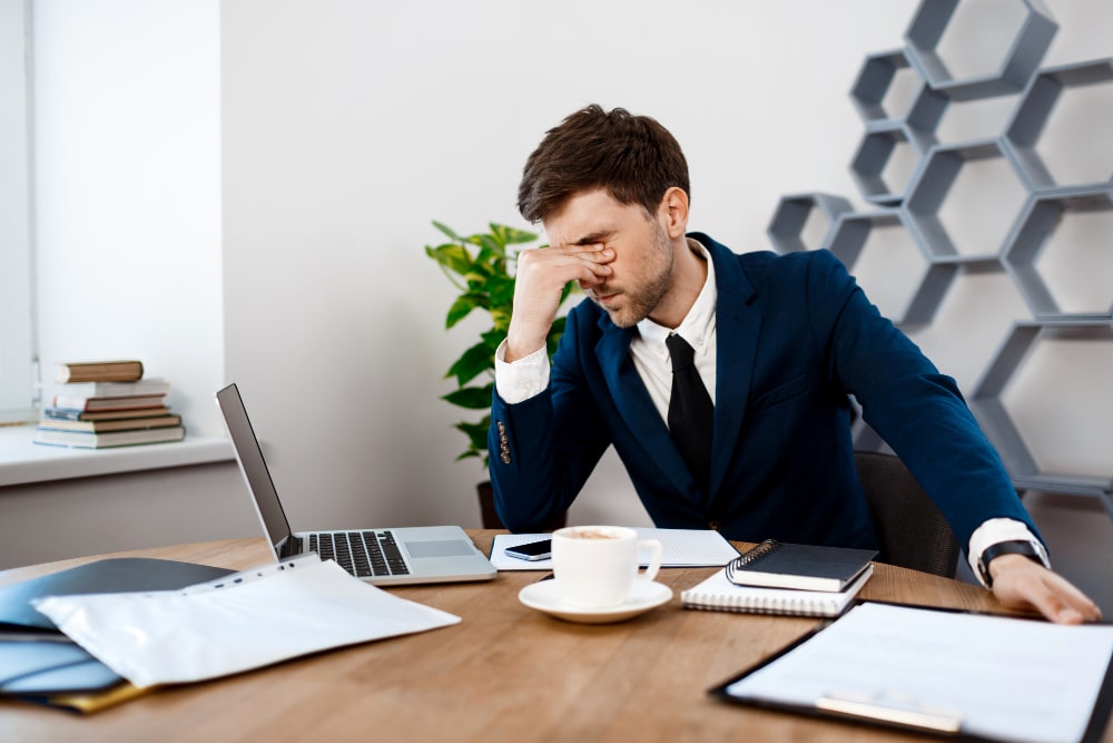 Employee holding his head with one hand while working